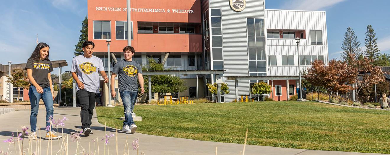 Students in walking on campus in front of a large building